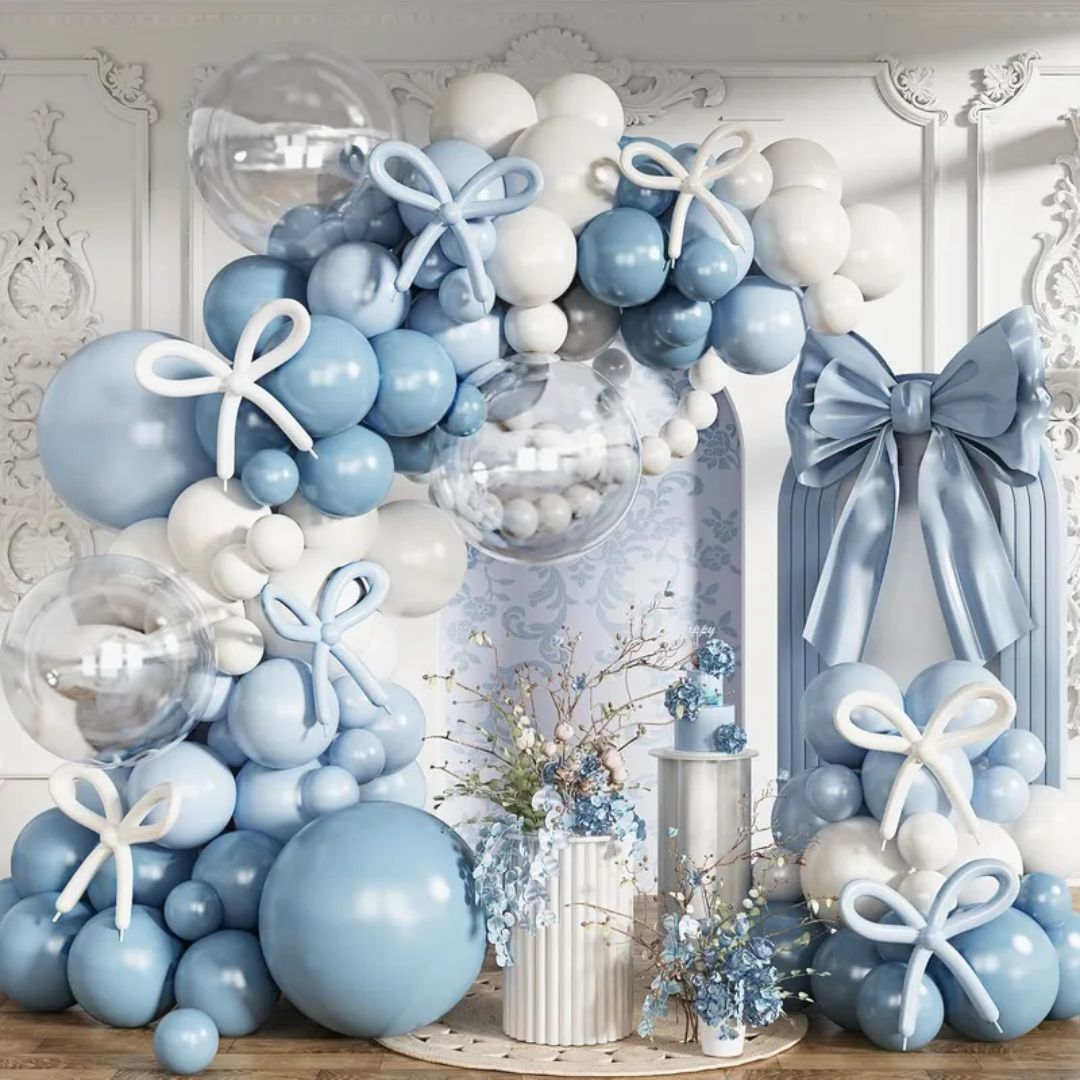 Decorative balloon arch with blue, white, and gray balloons and ribbons in a room setting.